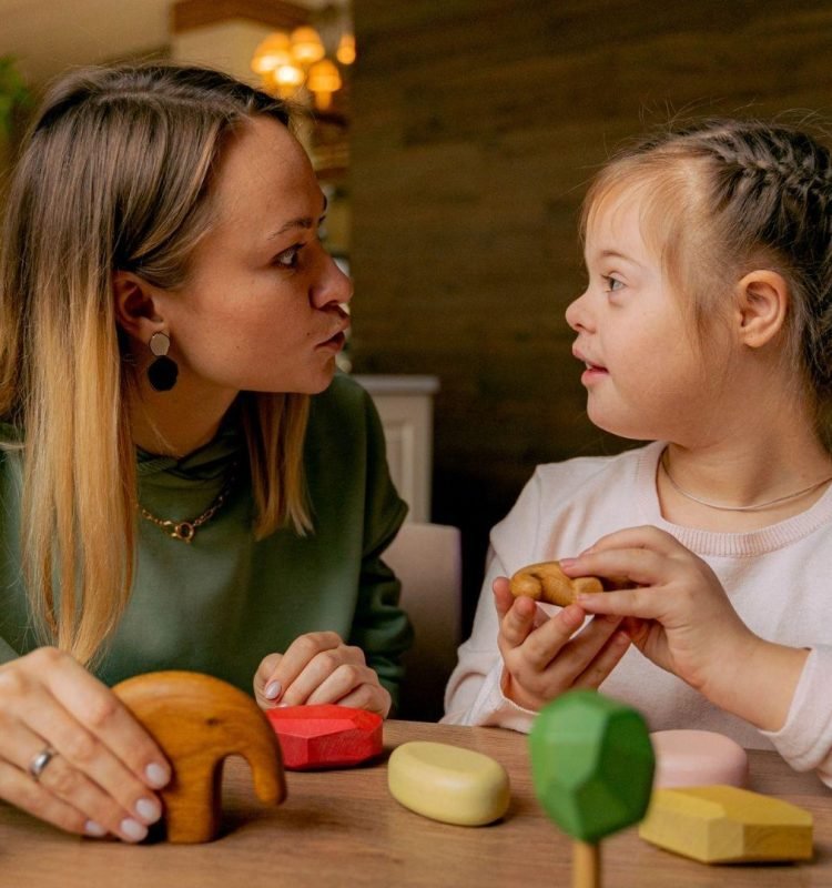 A caring support worker engaging with a young girl with Down syndrome while playing with wooden toys, symbolizing personalized disability care in Sydney.